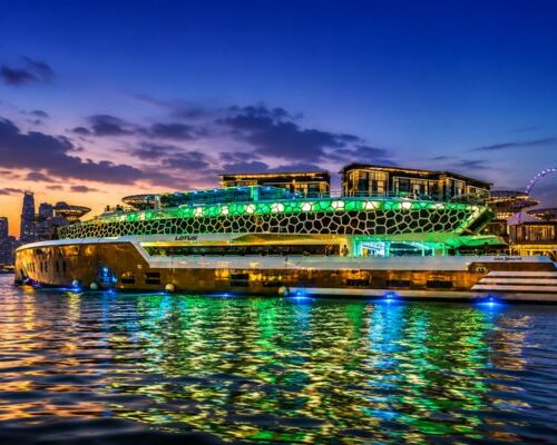 Premium Lotus Mega Yacht illuminated at night with Dubai Marina skyline